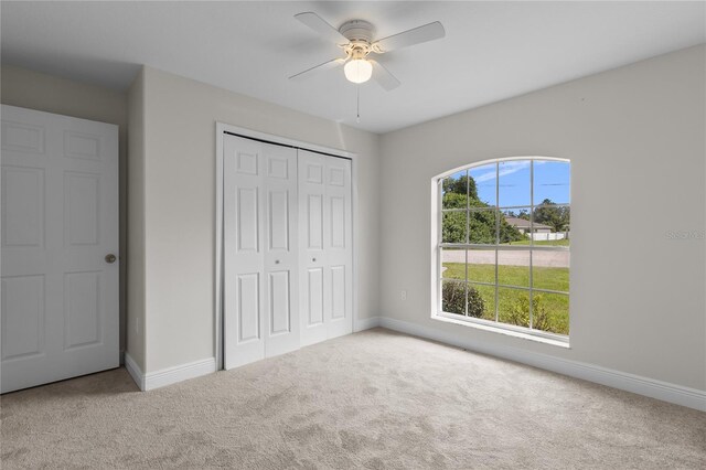 unfurnished bedroom with a closet, ceiling fan, and carpet floors