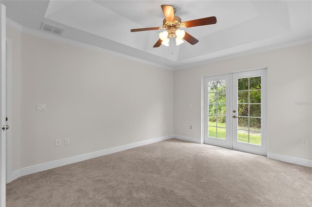 carpeted spare room featuring crown molding, a raised ceiling, french doors, and ceiling fan