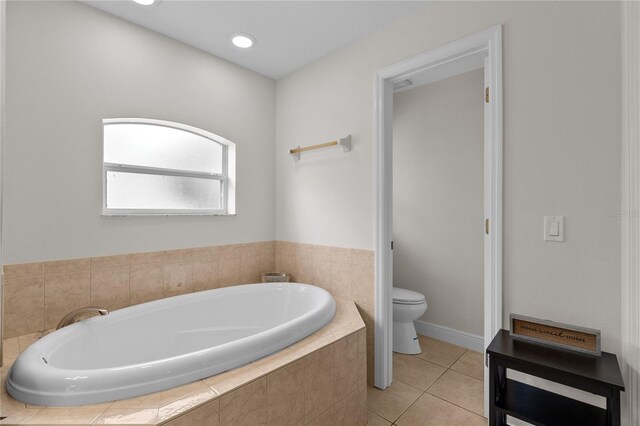 bathroom featuring tiled tub, toilet, and tile patterned floors