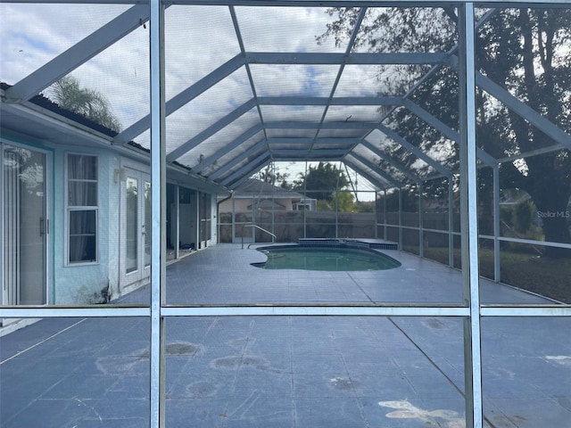 view of swimming pool with glass enclosure and a patio