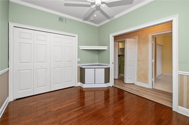 unfurnished bedroom featuring a closet, ceiling fan, crown molding, and wood-type flooring