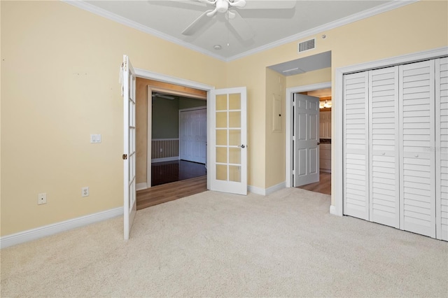 unfurnished bedroom featuring a closet, ceiling fan, carpet, and crown molding