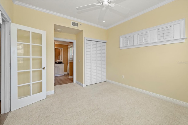 unfurnished bedroom featuring ceiling fan, ornamental molding, a closet, and light carpet