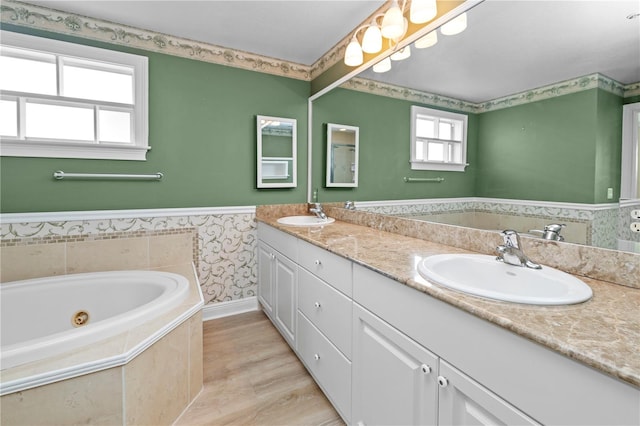 bathroom with hardwood / wood-style flooring, tiled tub, and vanity