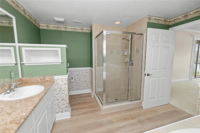 bathroom featuring vanity, a textured ceiling, hardwood / wood-style floors, and a shower with door