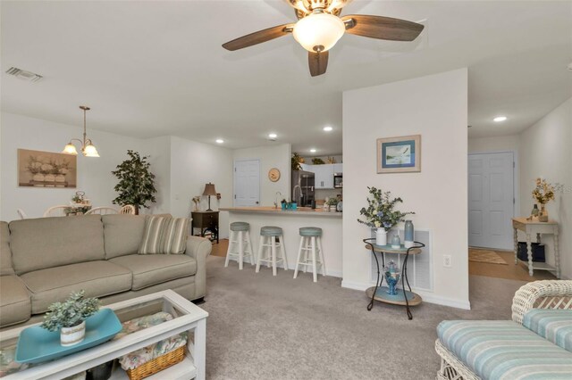 living room featuring ceiling fan with notable chandelier and light colored carpet