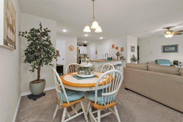 dining space with ceiling fan with notable chandelier and light colored carpet