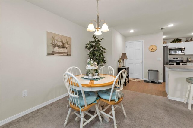 dining space with light colored carpet and a notable chandelier