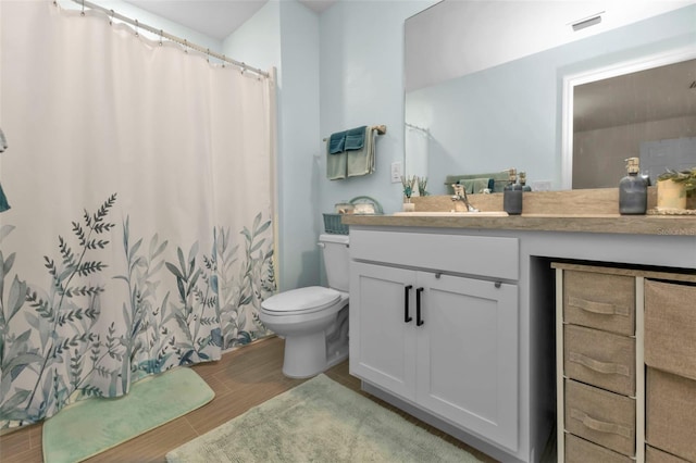 bathroom with vanity, toilet, hardwood / wood-style floors, and walk in shower