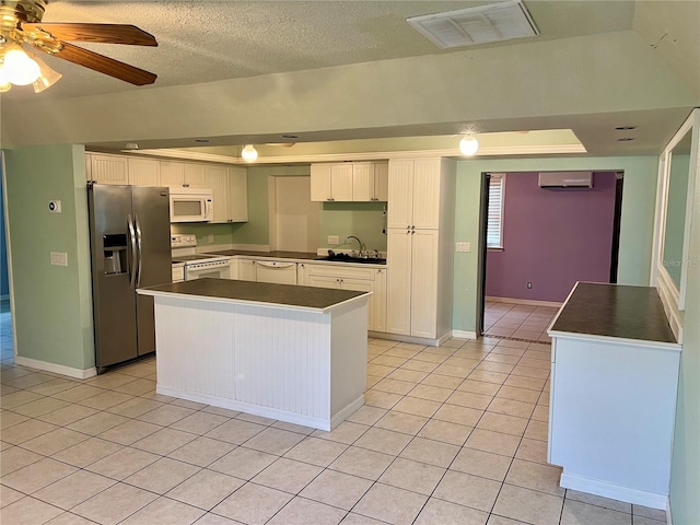 kitchen with white cabinets, white appliances, ceiling fan, a kitchen island, and a textured ceiling