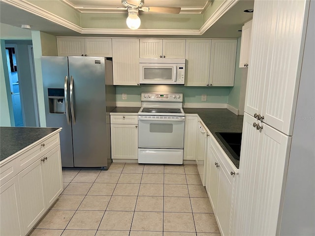 kitchen featuring crown molding, a raised ceiling, light tile patterned floors, and white appliances