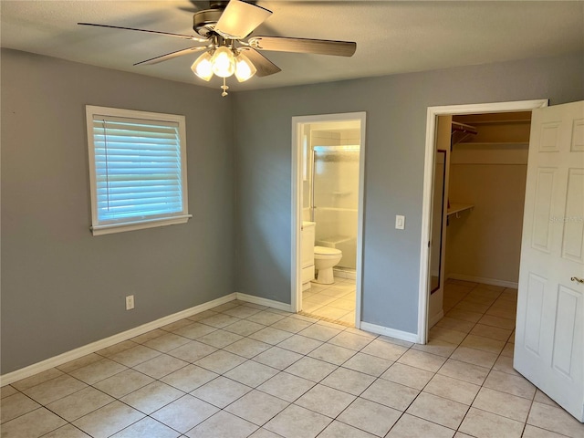 unfurnished bedroom featuring light tile patterned floors, ensuite bathroom, a walk in closet, a closet, and ceiling fan