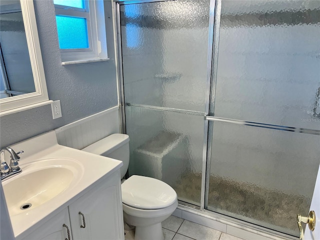 bathroom featuring vanity, toilet, tile patterned floors, and a shower with door