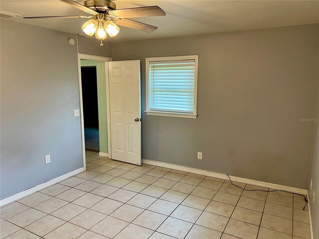 spare room with ceiling fan and light tile patterned floors