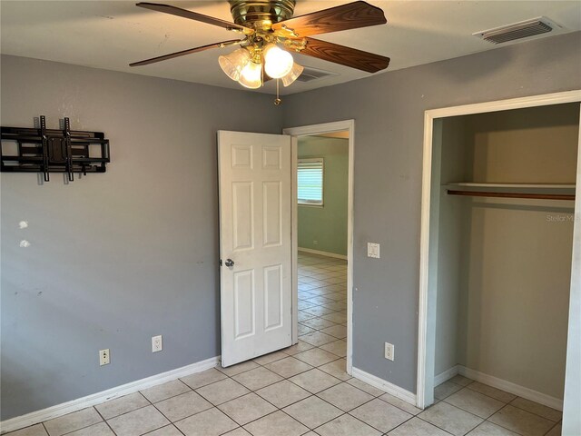 unfurnished bedroom with light tile patterned flooring, ceiling fan, and a closet