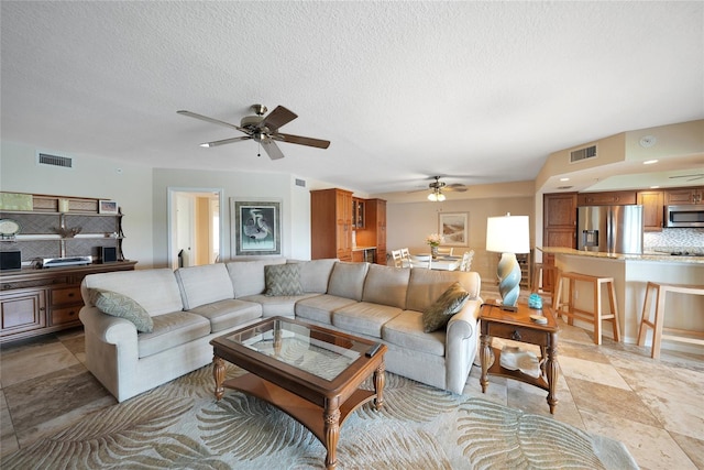 living room featuring a textured ceiling and ceiling fan