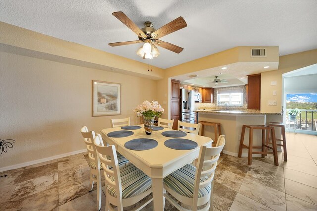 dining space with a textured ceiling and ceiling fan