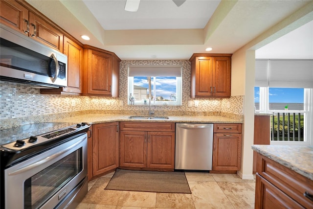 kitchen featuring plenty of natural light, stainless steel appliances, a raised ceiling, and sink