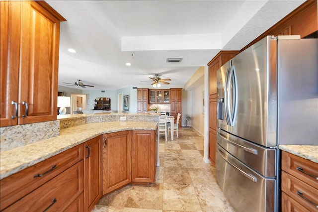 kitchen with ceiling fan, light stone counters, and stainless steel fridge with ice dispenser