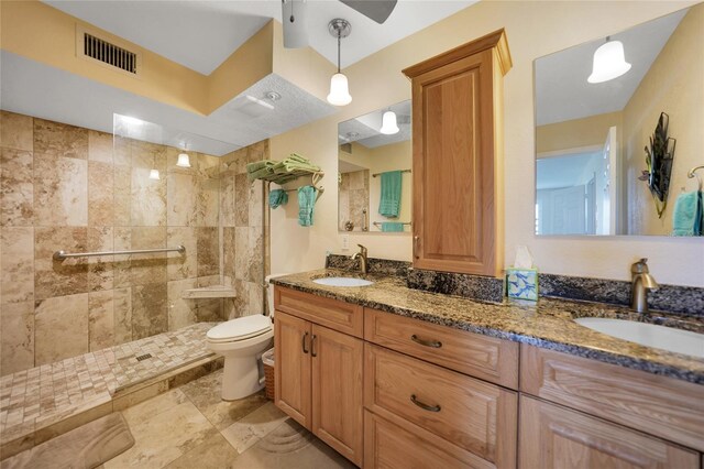 bathroom featuring vanity, toilet, and a tile shower