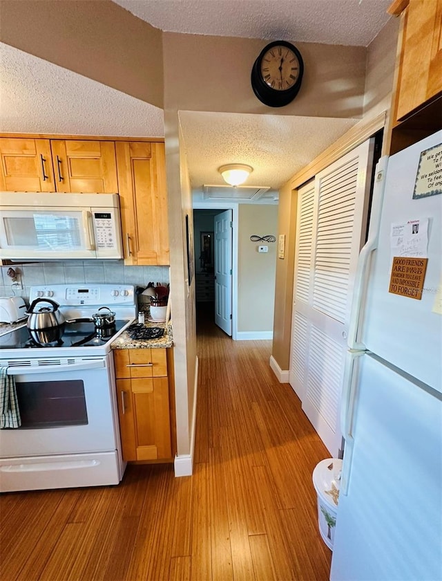 kitchen featuring white appliances, backsplash, a textured ceiling, and light hardwood / wood-style flooring