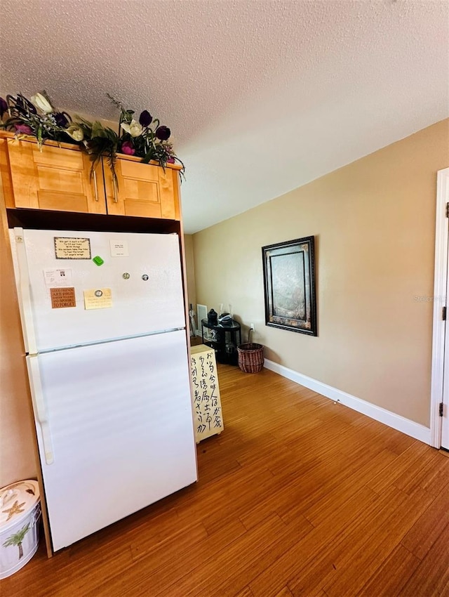 kitchen featuring a textured ceiling, wood-type flooring, and white fridge