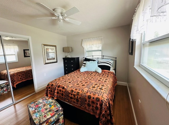 bedroom featuring multiple windows, a closet, ceiling fan, and dark hardwood / wood-style floors