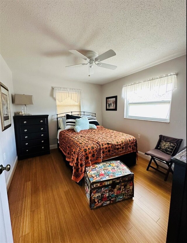 bedroom with a textured ceiling, hardwood / wood-style floors, and ceiling fan