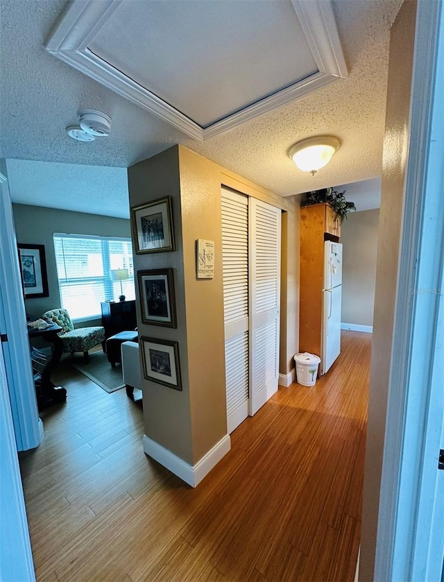 corridor with a textured ceiling and hardwood / wood-style flooring