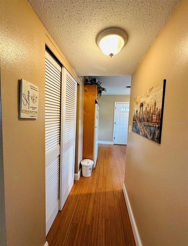 hallway with a textured ceiling and hardwood / wood-style floors