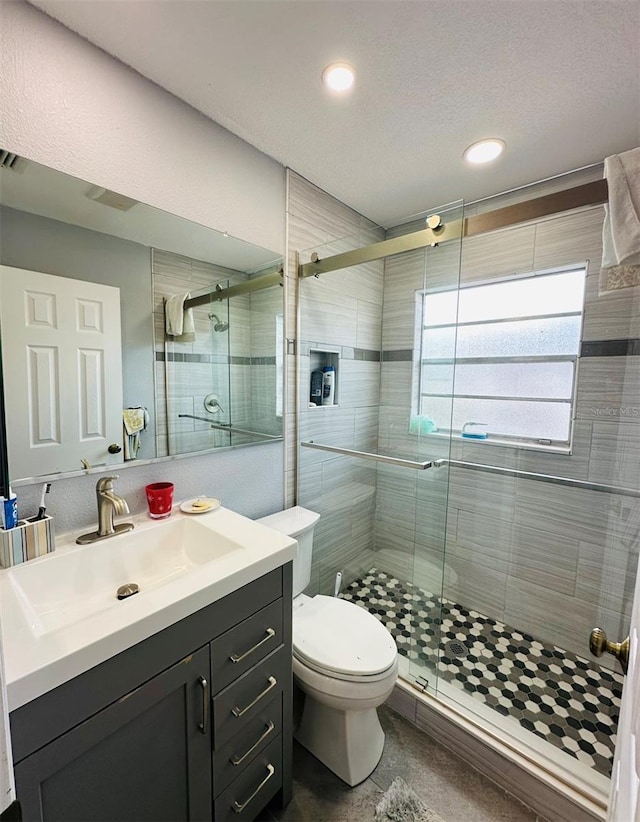 bathroom featuring toilet, a shower with door, a textured ceiling, and vanity