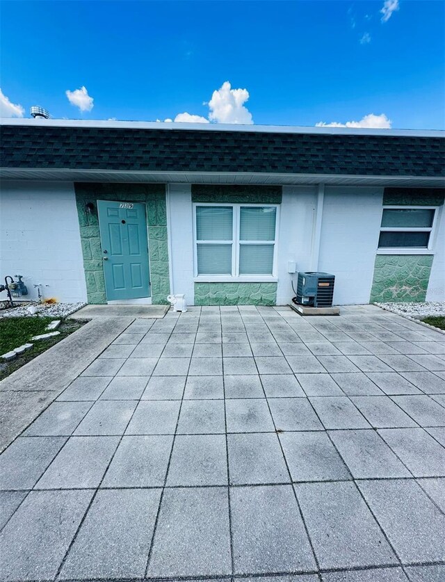 view of exterior entry with a patio and central air condition unit