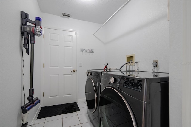 laundry area with light tile patterned floors and washer and clothes dryer