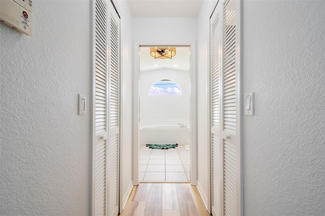 hall featuring light wood-type flooring and lofted ceiling