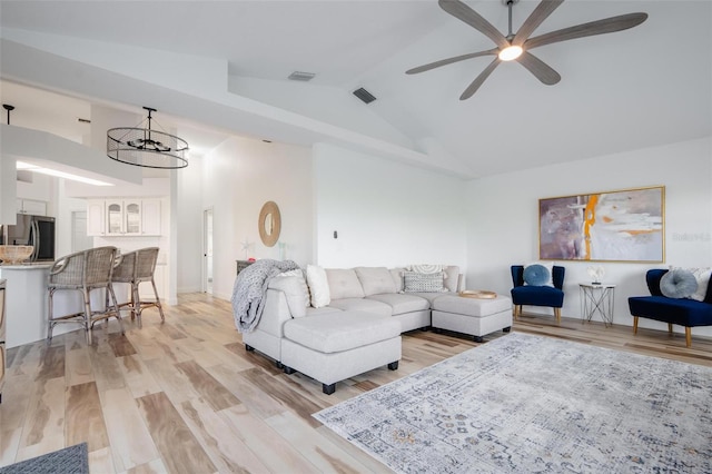 living room featuring light wood-type flooring, vaulted ceiling, and ceiling fan with notable chandelier