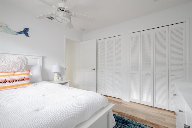 bedroom with ceiling fan, two closets, and light hardwood / wood-style floors