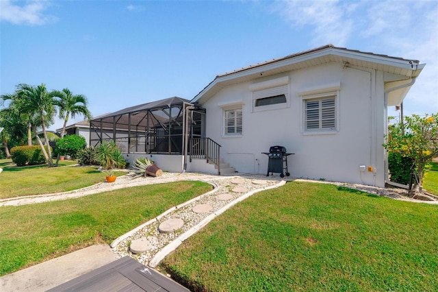 rear view of house with a yard and a lanai