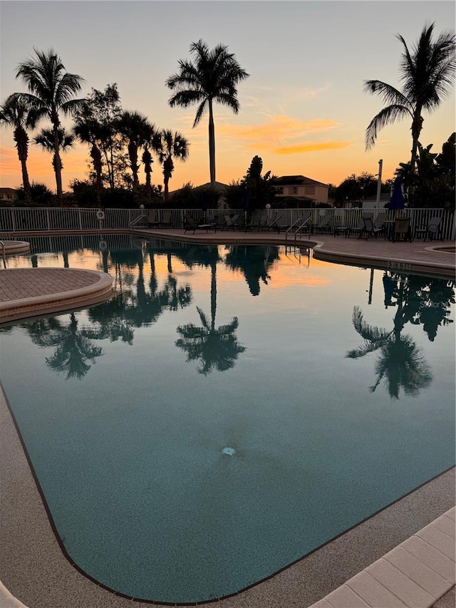 pool at dusk with a patio area