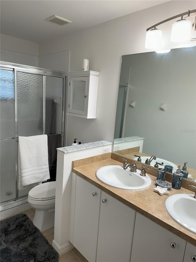 bathroom featuring toilet, a shower with door, and vanity