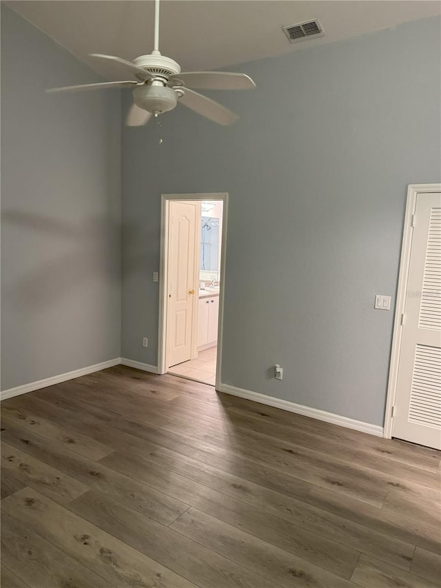 spare room with hardwood / wood-style flooring, ceiling fan, and a towering ceiling