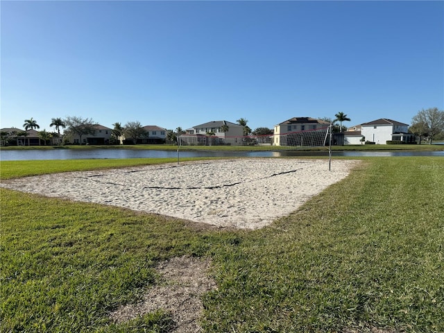 view of property's community featuring a water view, a lawn, and volleyball court