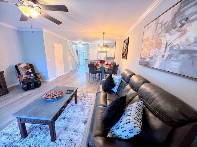 living room featuring crown molding, ceiling fan with notable chandelier, and light hardwood / wood-style floors