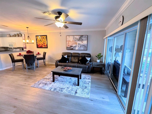 living room with ceiling fan with notable chandelier, crown molding, and light hardwood / wood-style flooring