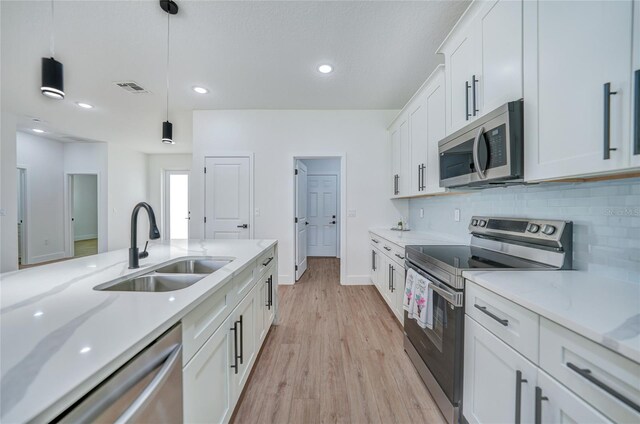 kitchen with decorative light fixtures, stainless steel appliances, sink, white cabinetry, and light wood-type flooring