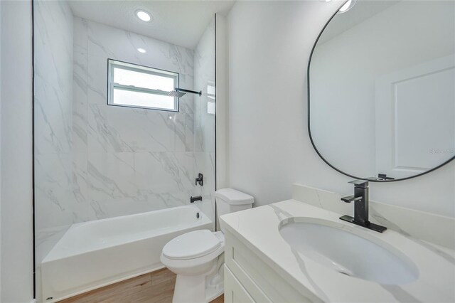 full bathroom featuring vanity, toilet, hardwood / wood-style flooring, and tiled shower / bath