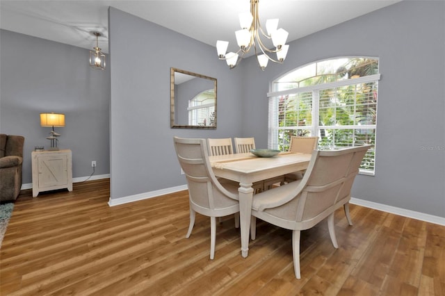 dining area featuring wood-type flooring and a notable chandelier