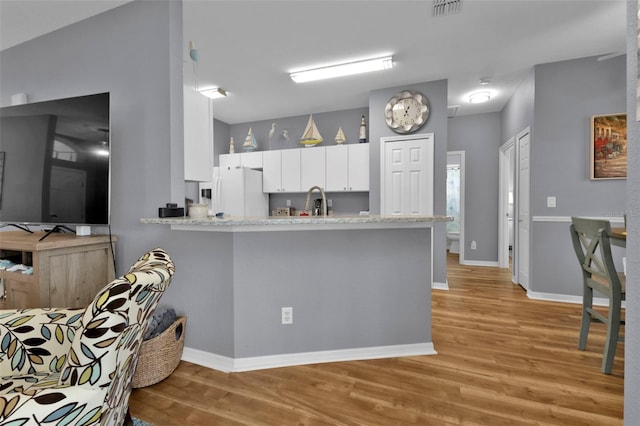 kitchen with light hardwood / wood-style flooring, kitchen peninsula, sink, white fridge with ice dispenser, and white cabinets