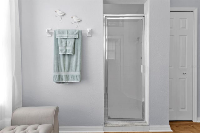 bathroom featuring a shower with door and hardwood / wood-style flooring