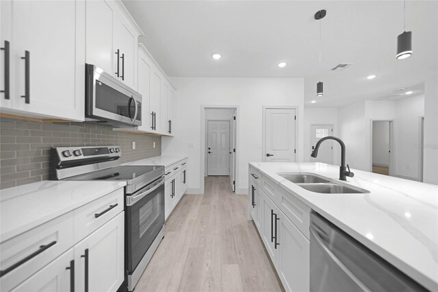 kitchen featuring white cabinets, light wood-type flooring, decorative light fixtures, stainless steel appliances, and sink