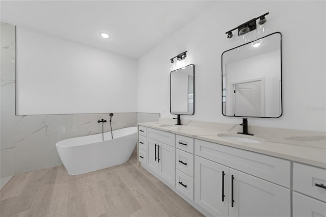 bathroom with vanity, a bath, and wood-type flooring